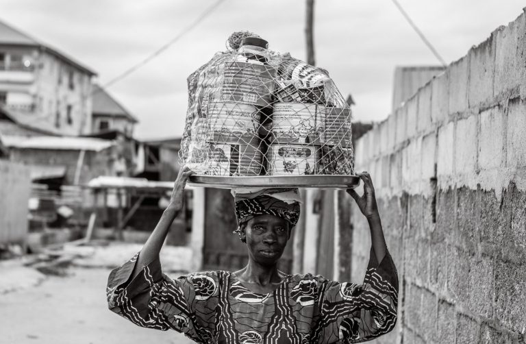 Dimoh, sets a tray on her head to hawk the containers she sells.